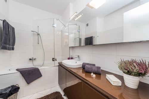 ein weißes Bad mit einem Waschbecken und einer Dusche in der Unterkunft Penthouse with roof terrace with jacuzzi in Zadar
