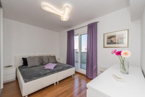 a bedroom with a bed and a window with purple curtains at Penthouse with roof terrace with jacuzzi in Zadar