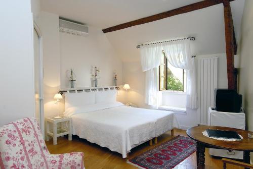 a bedroom with a white bed and a table and a chair at Le Vieux Pont in Belcastel