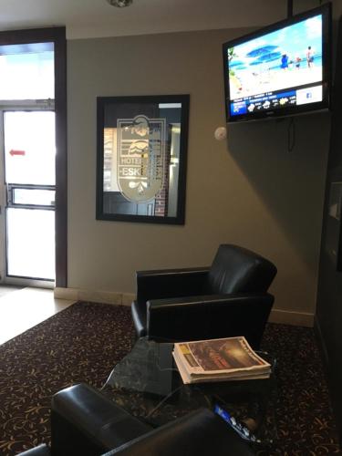 a living room with a couch and a tv on the wall at Hotel des Eskers in Amos