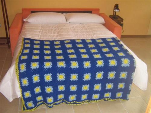 a bed with a blue and yellow blanket on it at Il Pergolato in Cannero Riviera