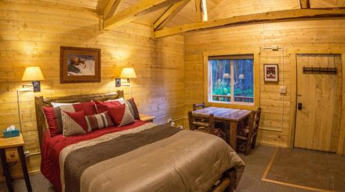 Schlafzimmer mit einem Bett, einem Tisch und einem Fenster in der Unterkunft Denali Tri-Valley Cabins in Healy