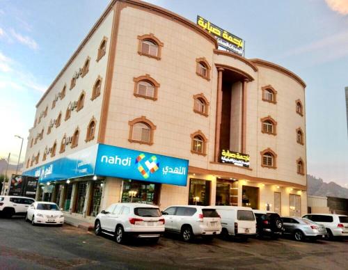 a large building with cars parked in front of it at Najmat Sabbabah Furnished Units in Hail