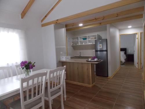 a kitchen and dining room with a table and a refrigerator at Cabañas Inadeqin in Ensenada