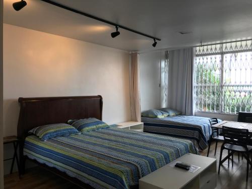 1 dormitorio con 2 camas, mesa y ventana en Atlantica Lofts, en Río de Janeiro