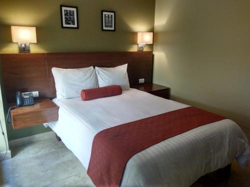 a bedroom with a large bed with a red pillow at Hotel Posada del Virrey in Xalapa