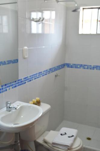 La salle de bains blanche est pourvue d'un lavabo et de toilettes. dans l'établissement Hotel Joohn Gay only LGBTIQ, à Melgar