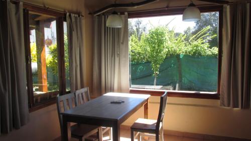 comedor con mesa, 2 sillas y ventana en Cabañas Peñi Huen en Lago Puelo