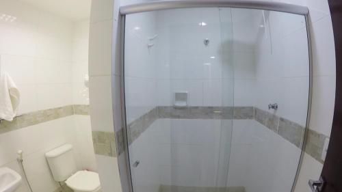 uma casa de banho com uma cabina de duche em vidro e um WC. em Hotel Coimbra em Tucuruí
