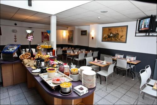 una sala da pranzo con tavolo e cibo di Hotel Primo Colmar Centre a Colmar