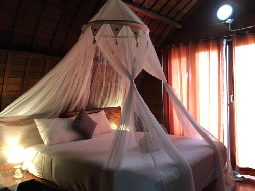 a bedroom with a bed with mosquito net at Bamboo Bungalow Jungle View in Nusa Penida