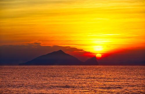 a sunset over the ocean with a mountain in the background at The Sunbeam Hideaway B&B in Luodong