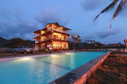 a house with a swimming pool in front of a house at The Tree House Sumbawa in Huu