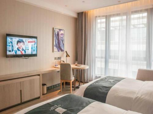 a hotel room with a bed and a desk and a television at 宜尚酒店厦门机场SM城市广场店 x 享机场接送 in Xiamen