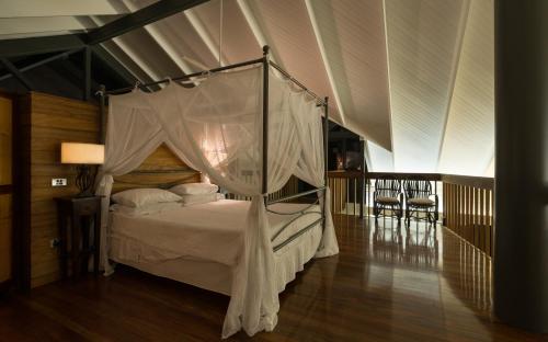 a bedroom with a canopy bed with white sheets and pillows at Sapphire Ridge in Palm Cove