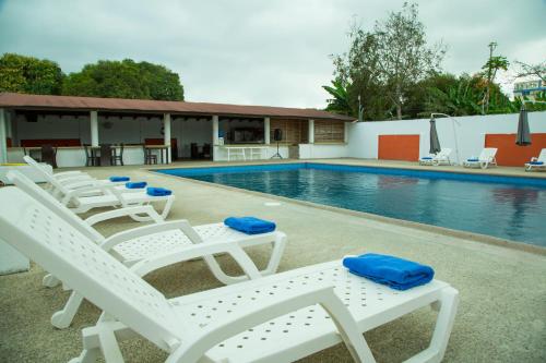 una piscina con tumbonas blancas y una piscina en Hotel RC Tonsupa en Tonsupa