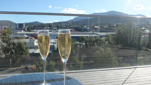 two champagne glasses sitting on a table in front of a window at Quarry House Luxury Retreat in Hobart