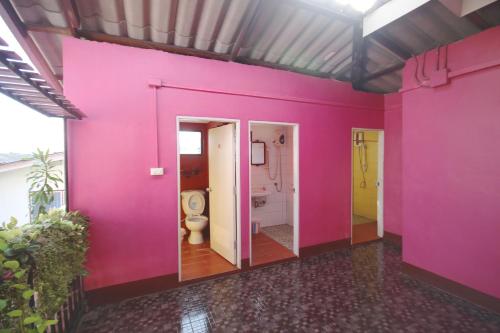 ein Bad mit einer rosa Wand und einem WC in der Unterkunft Baan Bua Homestay in Chiang Rai