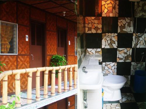 a bathroom with a toilet and a mosaic wall at Stefanie Grace Paradise Inn in Loboc