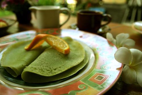 a plate of pancakes with an orange slice on top at Suryadina Guest House in Ubud