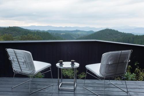 two chairs and a table on a balcony with mountains at Gekkoju Kurokawa in Minamioguni