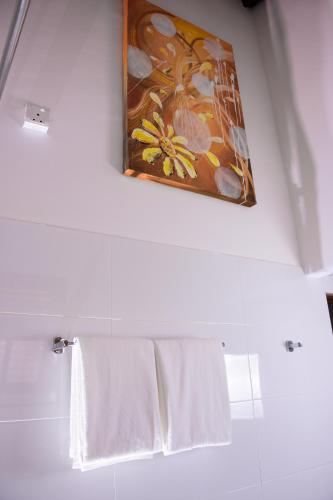 a bathroom with white towels and a painting on the wall at Channa Villa & Tours in Bentota