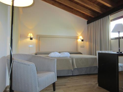 a hotel room with a bed and a chair at Balneario Cervantes in Santa Cruz de Mudela