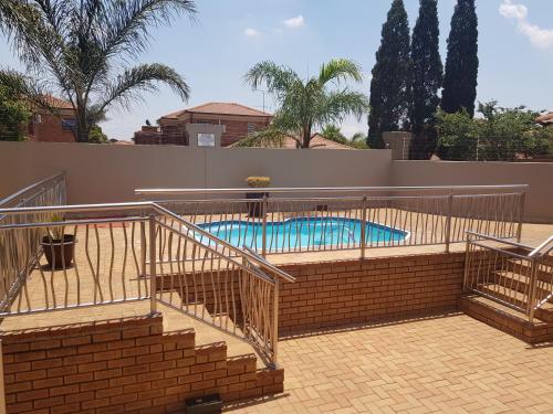 a swimming pool with stairs and a brick wall at Europrime Hotel in Boksburg