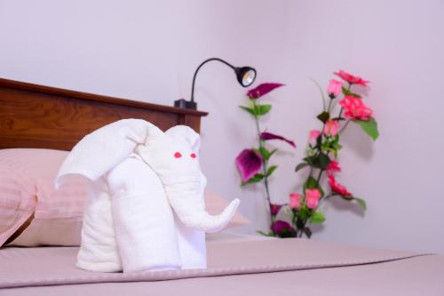 a white elephant toy on a bed with flowers at Channa Villa & Tours in Bentota