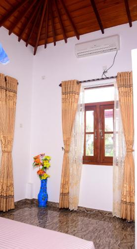 a room with curtains and a vase with flowers in it at Channa Villa & Tours in Bentota