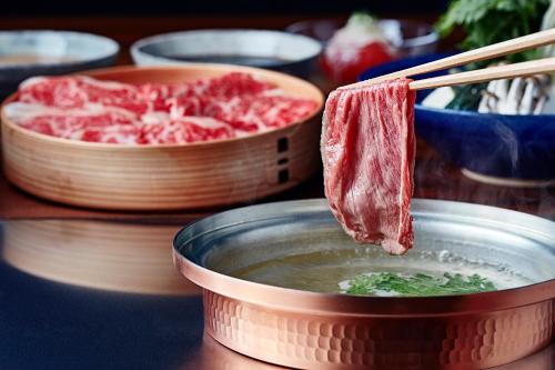 a piece of meat being dipped into a bowl of soup at Sotetsu Fresa Inn Ginza Sanchome in Tokyo