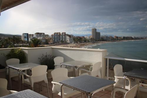 a balcony with tables and chairs and a view of the beach at Hotel Mare Nostrum in Peñíscola