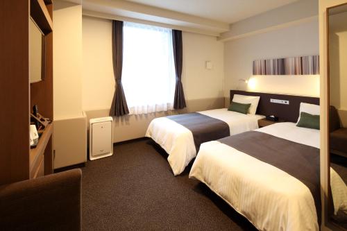 a hotel room with two beds and a window at Y's HOTEL Hanshin Amagasaki Ekimae in Amagasaki