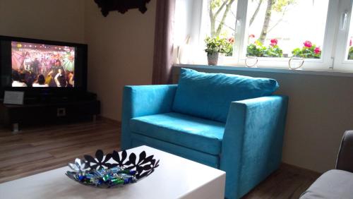 a living room with a blue chair and a tv at Gdynia Abrahama 23 in Gdynia