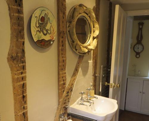 a bathroom with a sink and a mirror on the wall at Stream Cottage, 450 year old thatched cottage in Dedham