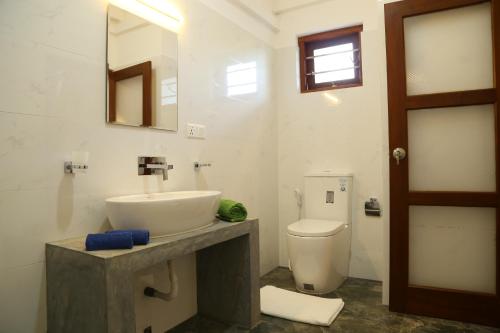 a bathroom with a sink and a toilet and a mirror at Hikka Regent Hotel in Hikkaduwa