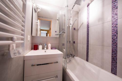 La salle de bains est pourvue d'un lavabo, d'une baignoire et d'une douche. dans l'établissement Résidence Grand Roc - Campanules 306 - Happy Rentals, à Chamonix-Mont-Blanc