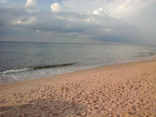 a sandy beach with the ocean on a cloudy day at Willa Olympia in Unieście