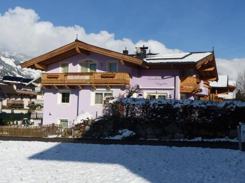 une maison rose avec un toit en bois dans la neige dans l'établissement Landhaus Nageler, à Westendorf