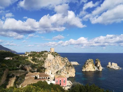a small island in the ocean with a lighthouse at Piccola Baia in Scopello