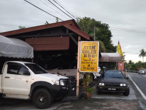 a white truck parked in front of a store with a yellow sign at D'Ashikin Village Stay in Seremban