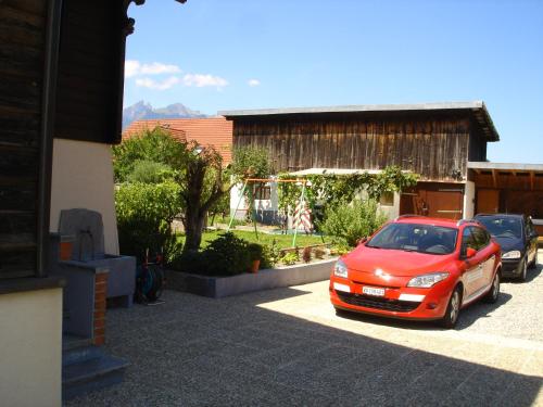 a red car parked in a parking lot at BnB Le Relais du Château in Aigle