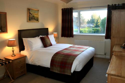 um quarto com uma cama grande e uma janela em Dawyk Beech Guesthouse em Fleet