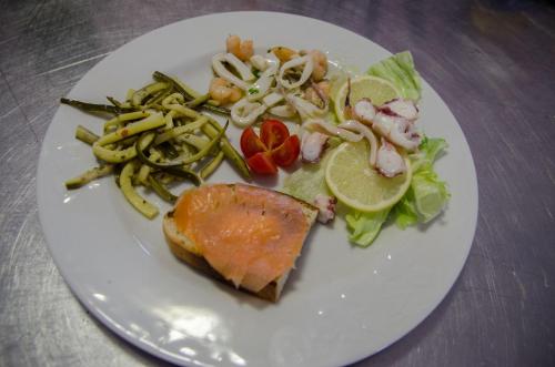 a white plate of food with a fish and vegetables at Holiday in Magliano deʼ Marsi