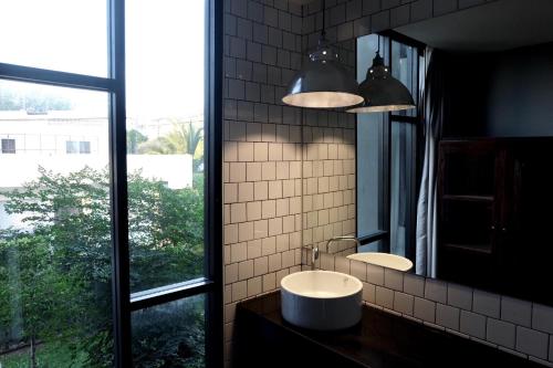La salle de bains est pourvue d'un lavabo, d'un miroir et d'une fenêtre. dans l'établissement Antique Chiangmai, à Chiang Mai