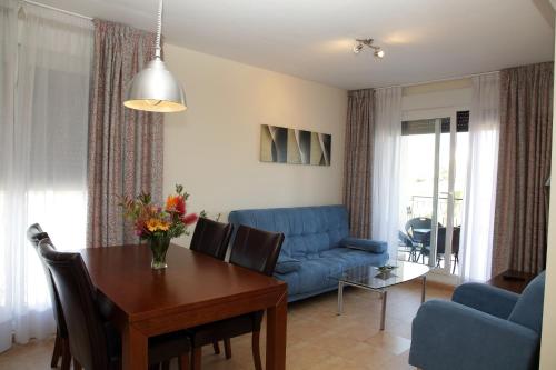 a living room with a table and a blue couch at Apartamentos Turisticos Aguilas de los Collados in Águilas