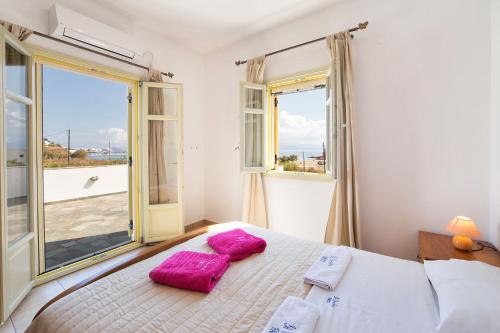 a bedroom with a bed with two pink pillows on it at Villa San Dimitrio House on the Beach in Logaras