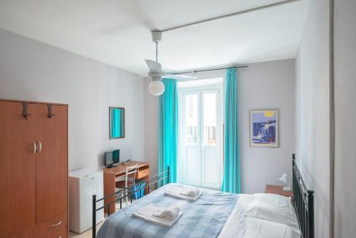 sypialnia z łóżkiem z niebieskimi zasłonami i oknem w obiekcie Gialel Guesthouse w Rzymie