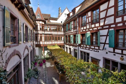 an alley of buildings with potted plants and flowers at Relais & Châteaux La Maison Des Têtes in Colmar