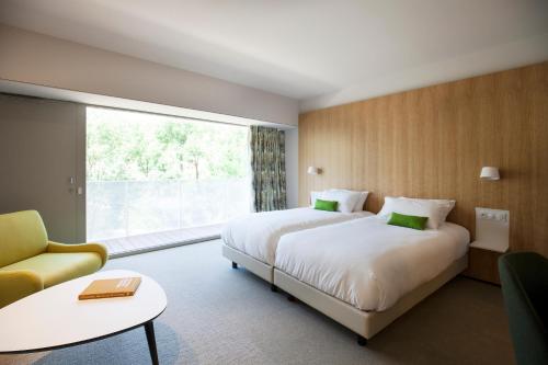 a hotel room with two beds and a large window at Best Western Plus Hotel Divona Cahors in Cahors